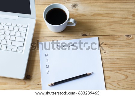 Paper check list for mission laptop and coffee on wood table. Royalty-Free Stock Photo #683239465