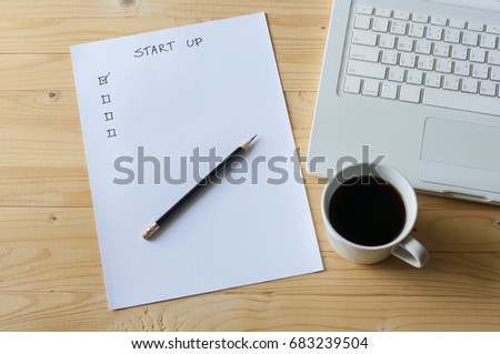 Paper check list for start up business laptop and coffee on wood table. Royalty-Free Stock Photo #683239504