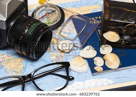 Passports on a map of the world.Camera, sunglasses, and seashells in the backgroun