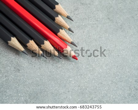 Red pencil standout from black pencil bare cement or concrete wall background, leadership business concept