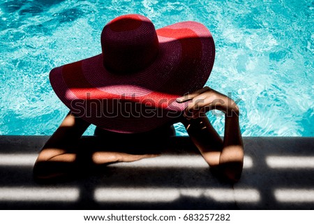 Silhouette of beautiful woman with a hat in the pool