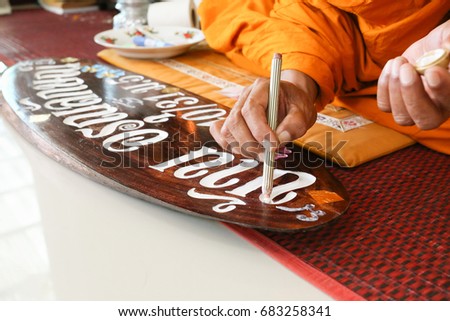 Monk makes blessed mark on wood board Thai translation means "Home of sunshine"