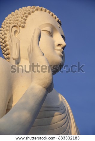 White huge Buddha Statue in Abhaya Mudra hand pose - traditional symbolic finger gesture, symbolizing safety and no fear, located at the top of Mahinda's Hill, Mihintale Temple, Sri Lanka, South Asia.