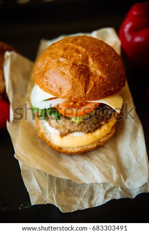 Big sandwich - hamburger with juicy chicken burger, cheese, tomato, and onion on wooden background