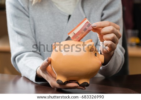 woman putting business card in a funny piggy bank. Concept of future, business, saving money, economy and investment