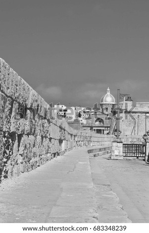 Narrow street along the wall of fortress on the island of Malta in historical part of Valletta. Black and white picture