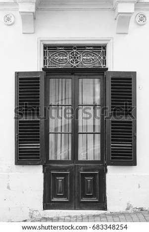 Traditional maltese door with ornamental metal lattice and shutters. Black and white picture