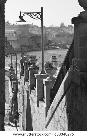 Street along the wall of fortress leading to the sea on the island of Malta in historical part of Valletta. Black and white picture