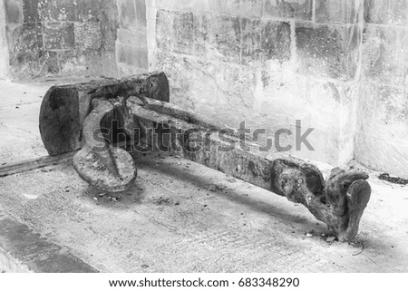 Old rusty anchor on the background of the wall on Malta. Black and white picture