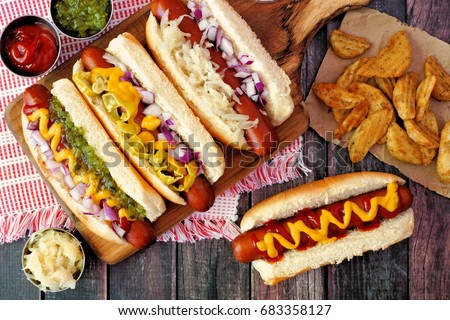 Hot dogs with assorted toppings and potato wedges, above view on a rustic wood background Royalty-Free Stock Photo #683358127
