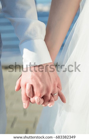 Bright sunny picture where the couple gently holding hands closeup