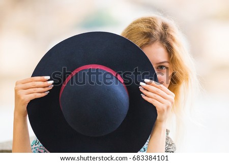 Portrait of the beautiful fashionable girl playing with hat outdoor