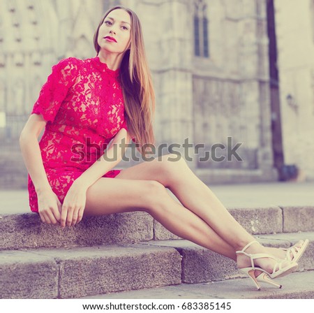 portrait of young smiling swiss adult girl in evening apparel sitting in european town
