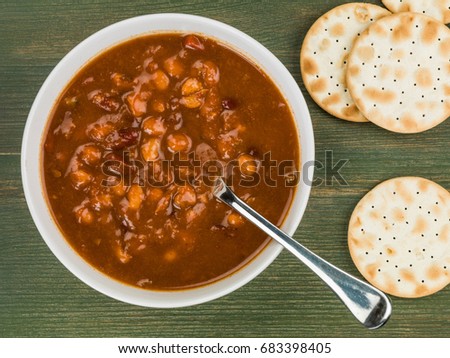 Bowl of Thick Chunky Vegetable and Bean Soup Against a Green Wooden Background