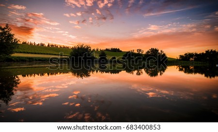 Italy June 2017. Lake at sunset with clouds and orange sky
