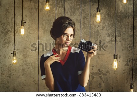 Woman model in vintage look holding retro camera in her hands