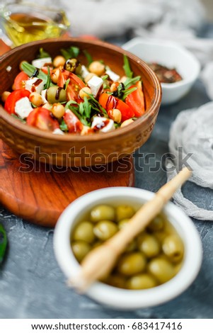 Spring vegetable salad with arugula, cherry tomatoes, chickpeas, olives and feta cheese. Buddha bowl. Healthy, vegan, detox food. Shallow depth of field.
