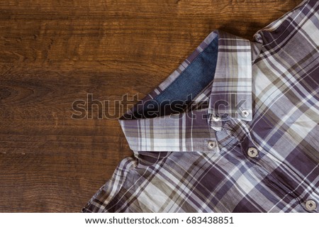 checked shirts on the brown wooden background. with copy space. top view.