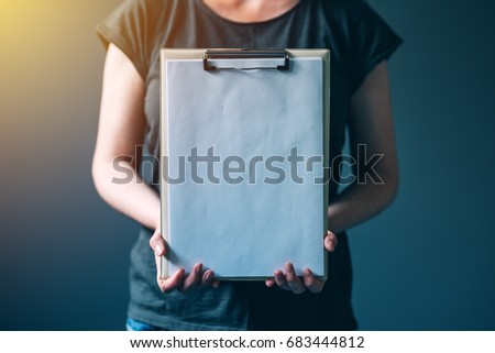 Casual caucasian adult woman holding blank notepad paper as copy space