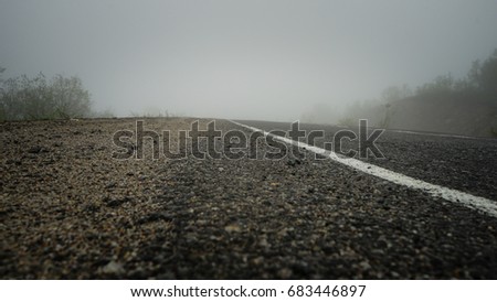 The road under a fog. Summer time in russian tundra region in mountains. Picture made from bottom.