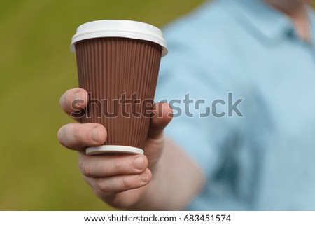 Man holding empty paper coffee cup. Template mock up