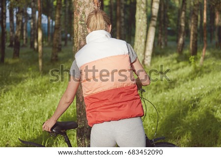 Young female biker next to her bike in a park.