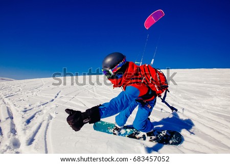 Snowboarder with a kite on fresh snow in the winter in the tundra of Russia against a clear blue sky. Teriberka, Kola Peninsula, Russia. Concept of winter sports snowkite. Royalty-Free Stock Photo #683457052