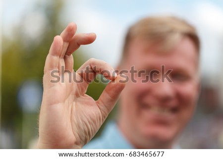 Portrait of cheerful young man showing okay gesture. Emotions and success concept.