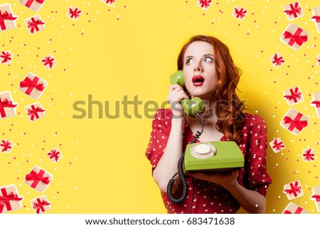 Surprised redhead girl in red polka dot dress with green dial phone on yellow background.