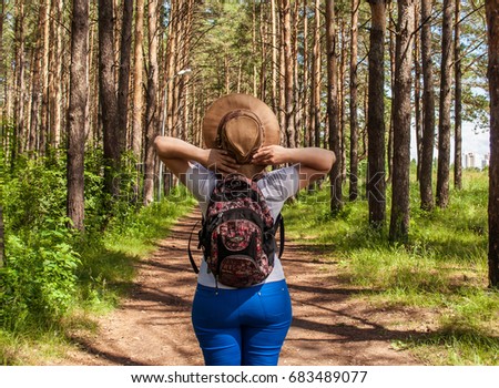 An enthusiastic girl walks through the woods with a backpack, the concept of tourism and hikes