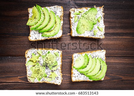 Sandwiches from bread with slices, zvezdami, hearts from avocado and curd cheese on a brown wooden background.