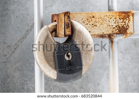 Round locked metal padlock securing a gate grill