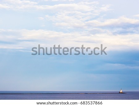 Cloudy Sky with Lighthouse and Breaker Wall at Sunset After Storm