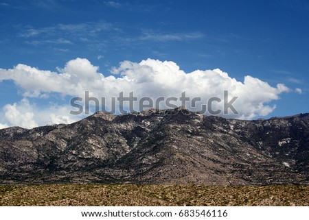 Close up isolated photo of a Santa Catalina  mountain top with puffy white clouds and blue sky in the Tucson Arizona desert 