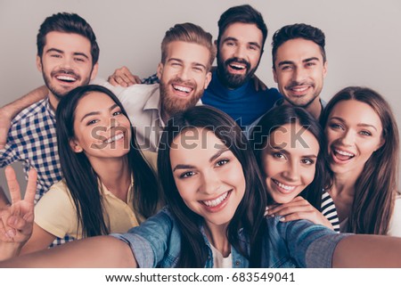 Cheers! Funky mood. Close up of an eight excited friend`s selfie, taken by brunette girl. Young people enjoy their company, smile, have fun