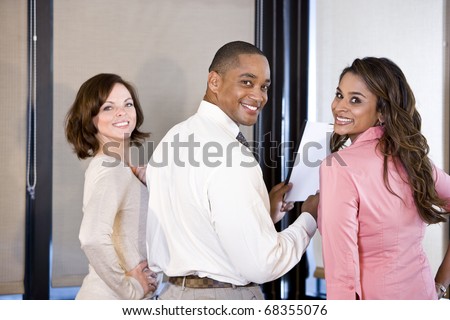Three multiethnic office workers reading report in boardroom, focus on couple on right