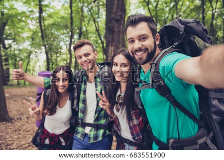 Close up of four cheerful  friends in the spring nice wood, embracing, posing for a selfie shot, that handsome brunet is taking