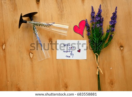 Lavender and will you marry me text on a white note and two grasses on wooden background