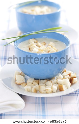 Two blue bowls of onion pureed soup with croutons and leek