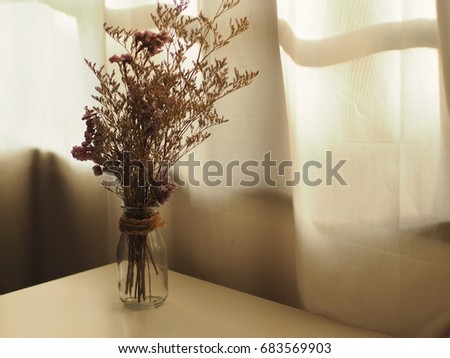 Flowers are not dry in the vase on the table by the window.
