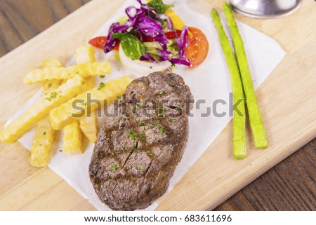 Closeup of a delicious grilled beef steak with spices and salad on wooden table in the restaurant