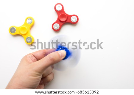 Hand playing with a spinner. Stress relieving toy on white background. Close-up. Top view. Nobody. Stock photo