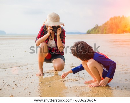Vacation summer and travel concept. Pretty woman photographing her kid at tropical beach.