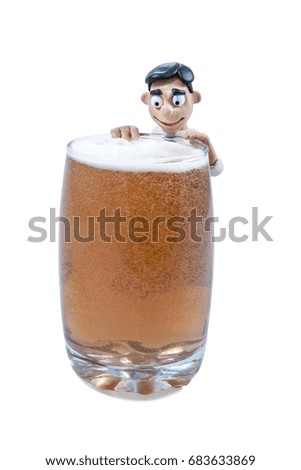 Small plasticine man hanging on a glass with beer isolated on white background
