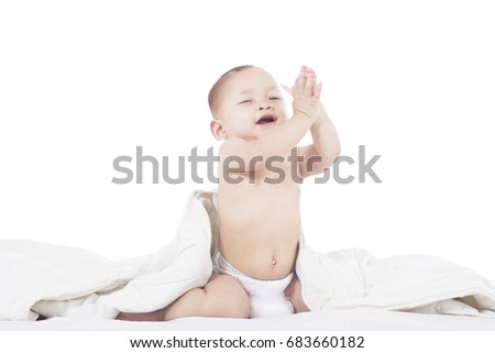 Picture of an adorable baby looks happy while playing in the bed, isolated on white background