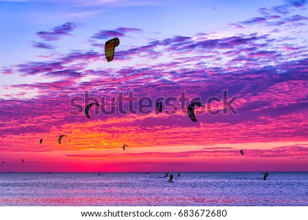 Kite-surfing against a beautiful sunset. Many silhouettes of kites in the sky. Holidays on nature. Artistic picture. Beauty world