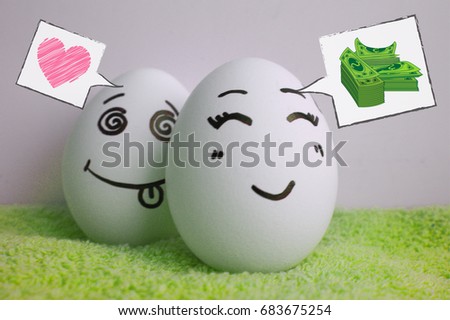 The concept of choice. Love or money. Eggs are cheerful with a face. Two pieces. Concept of hide and seek game. Photo for your design