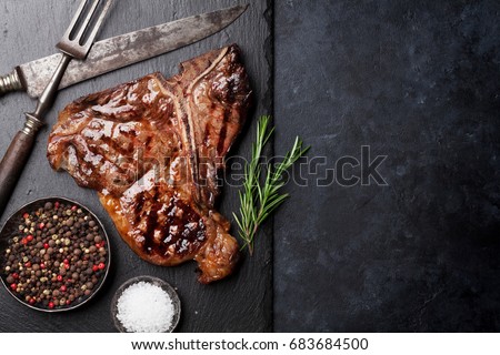 Grilled T-bone steak on stone table. Top view with copy space Royalty-Free Stock Photo #683684500