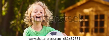 Smiling little boy playing football in the house garden