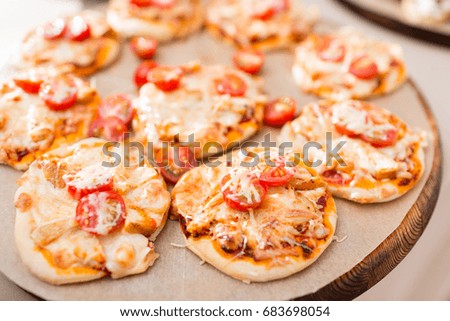 a lot of mini pizza, on wood plate. catering buffet. soft focus